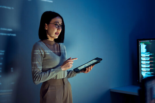 asian woman programmer standing in front of a screen with code projected  presentation the integration of technology and human expertise in software development