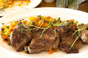 Meat, beef medallions with vegetables on a plate with microgreens.