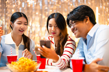 Group of Asian male and female friends Having fun at a house party Take a selfie with a group of friends using your smartphone. A room lit up with  lights. New Year's Eve party idea