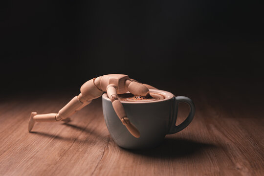 Tired wooden doll lying on a cappuccino cup