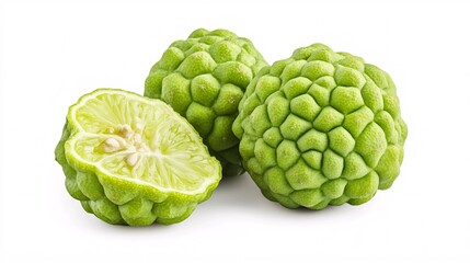 Fototapeta premium Three vibrant green bergamot fruits with one cut in half, showcasing its juicy interior.