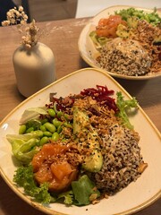 Poke bowl with quinoa, salmon, avocado, feta cheese on a wooden background