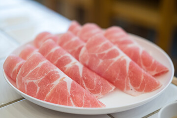 A close up of thinly sliced pork for hotpot, detailed marbling and fat. Pork platter