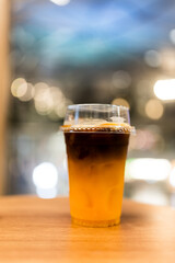 Iced americano with orange juice in take away cup with light bokhe
