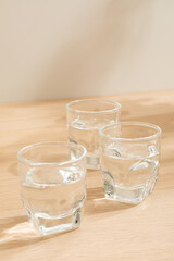 Glass of water isolated on wooden background. Warm lighting background. Wooden surface. Light and Shadow wallpaper. Space for text. Backdrop. Studio photography. Still life. 