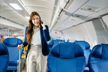 Asian female passenger of airplane sitting in comfortable seat while working laptop and tablet. Travel in style,