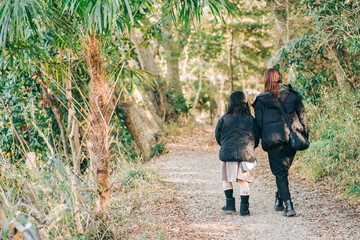 冬の森の中を歩くお母さんと子供