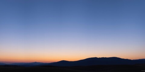 Obraz premium Serene Sunset Over a Distant Mountain Range, Painted in Hues of Orange and Blue