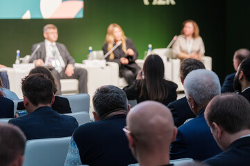 Corporate panel discussion with a formal audience in attendance making observations and notes. Ideal for concept of business communication and professional interaction.