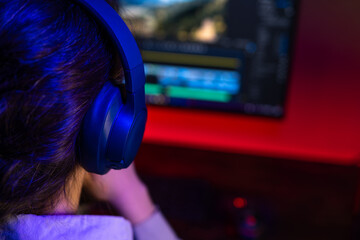 Girl sitting at desk with headphones in dark