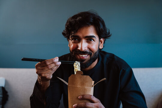 Pakistani guy with traditional outfit eating noodles.