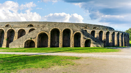 Obraz premium landscape of old ancient building of Roman arena with greeen grass foreground and beautiful blue cloudy sky background