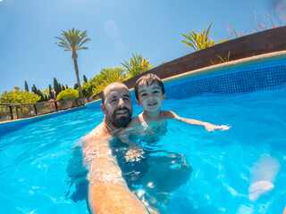 Father and son enjoying swimming pool on summer vacation