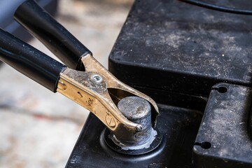 Close-up of car battery terminal with attached jumper cable.