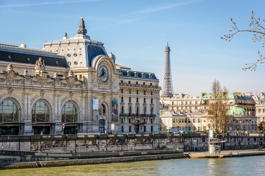 Paris, France - March 14, 2018: Facade of the former Orsay train station which houses the Orsay museum since 1986, with the Eiffel tower in the background and the Seine in the foreground.