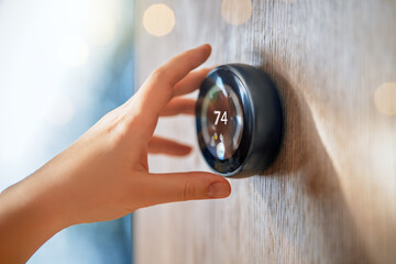 The hand reaching for the thermostat