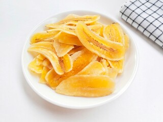 Close-up of banana chips in plate on white background.