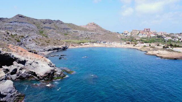 Cala reona beach features turquoise waters and tourists enjoying summer vacations in la manga, murcia, spain
