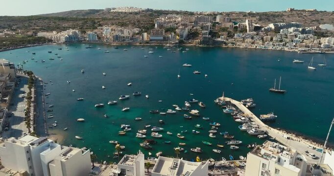 Aerial view of the marina in Bugibba, Malta. Mediterranean seascape with yachts and fishing boats near the quay, tourism and travel in the Mediterranean. High quality 4k footage