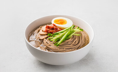 Naengmyeon, Korean cold noodles in a white bowl. Traditional Asian food, selective focus