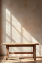 Fototapeta premium A clean wooden desk against a pale beige wall with a large blank space at the center, softly illuminated by sunlight from a nearby window. 