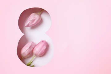 Paper cut out figure eight on pink background with fresh tulips. Concept of 8 march, Women's day