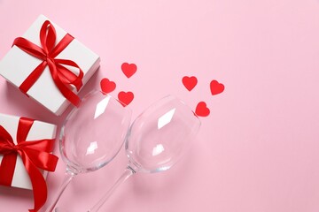 Fototapeta premium Wine glasses, gift and red hearts on color background, top view