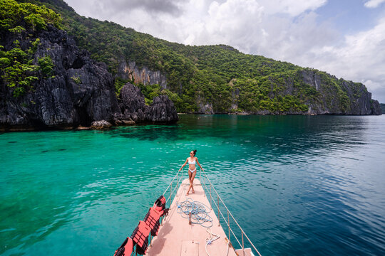 Young woman in bikini standing on the boat prow, El Nido