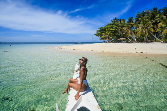 Young asian woman sitting on boat prow, Guyam island, Siargao