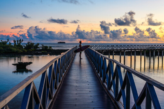 Man with surfboard on jetty at sunrise, Cloud 9, Siargao island, Philippines