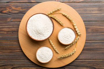 Flat lay of Wheat flour in wooden bowl with wheat spikelets on colored background. world wheat crisis