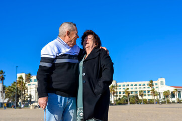 Happy retired couple smiling and embracing on beach vacation