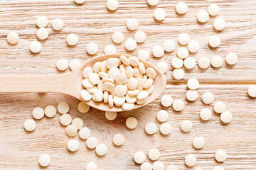 Heap of white pills on colored background. Tablets scattered on a table. Pile of red soft gelatin capsule. Vitamins and dietary supplements concept