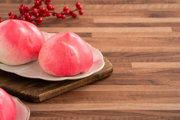 Pink Chinese peach birthday bun food shoutao on wooden table background.