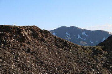 Rugged mountain landscape with rocky terrain and snow patches.