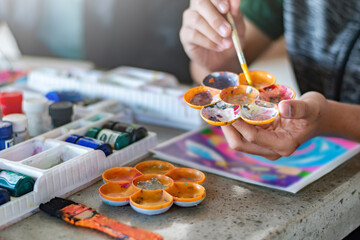 Learning to use poster color to draw various pictures of asian boys on a table outside classroom with his female art teacher, raising teen and adult helps kids school project concept.