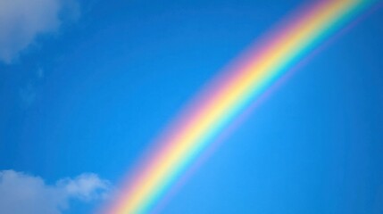 A vibrant rainbow arching across a clear blue sky with fluffy white clouds.