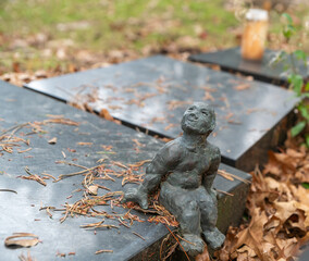 Kleine Figur sitzt auf einem Grabstein