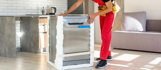 Master installing the dishwasher in a kitchen cabinet