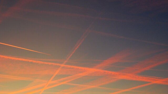 Ciel du cr&eacute;puscule barbouill&eacute; de stries  laiss&eacute;es par des avions &eacute;clair&eacute;es par le soleil