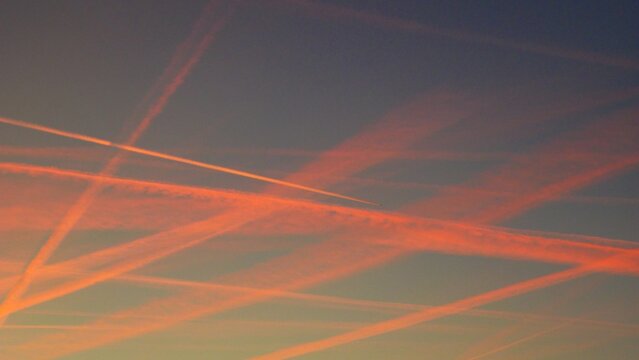 Ciel du cr&eacute;puscule barbouill&eacute; de stries  laiss&eacute;es par des avions &eacute;clair&eacute;es par le soleil