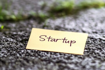 Single Sticky Note Featuring the Word Startup on a Textured Surface