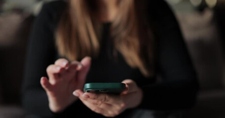 Close-up young woman using smartphone in living room at home. Girl using texting mobile phone or chat. Chatting on social networks online. - Powered by Adobe