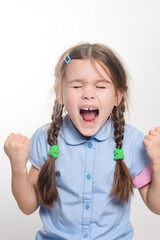 A close-up shot of a young girl with long brown braids, wearing a light blue shirt. She's screaming...