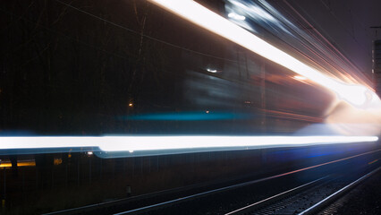 beams of lights from a passing train on a railway at night