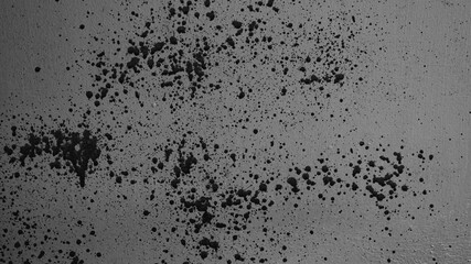 The photo shows a grey wall with splashes, streaks and blots of black paint