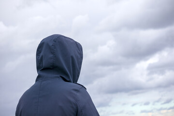 A man in a black coat on the background of a blue sky with clouds