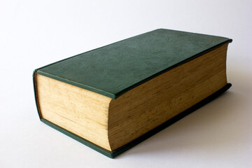 A green leathered closed dictionary book with aged brown papers, indicating that the book is old.