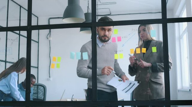 Bunch of stickers on the glass. Professional workers are in the modern office together.