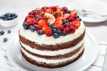 Delicious chocolate sponge cake with berries served on light table, closeup